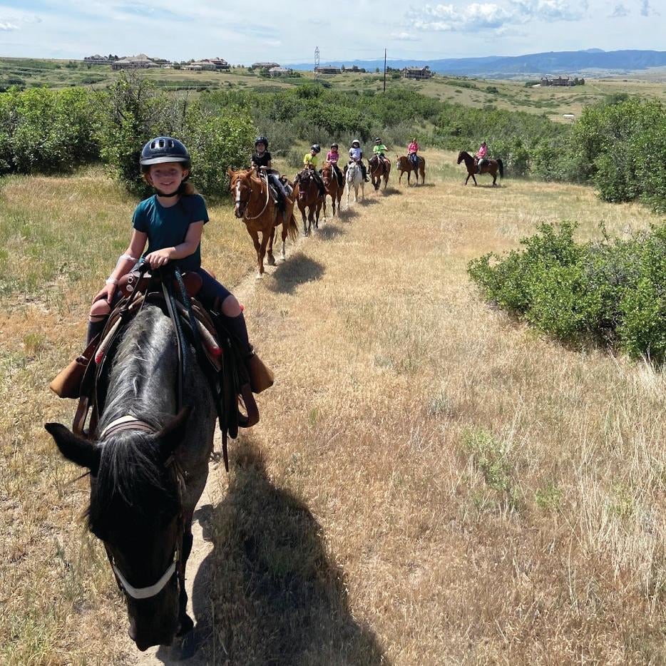 Photo of children riding horses neatly in a row. 