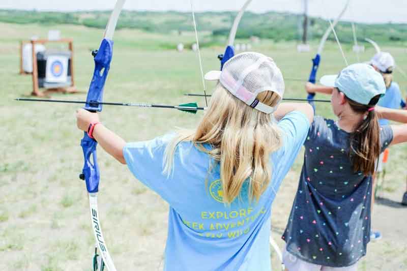 Two kids at an archery range shooting arrows